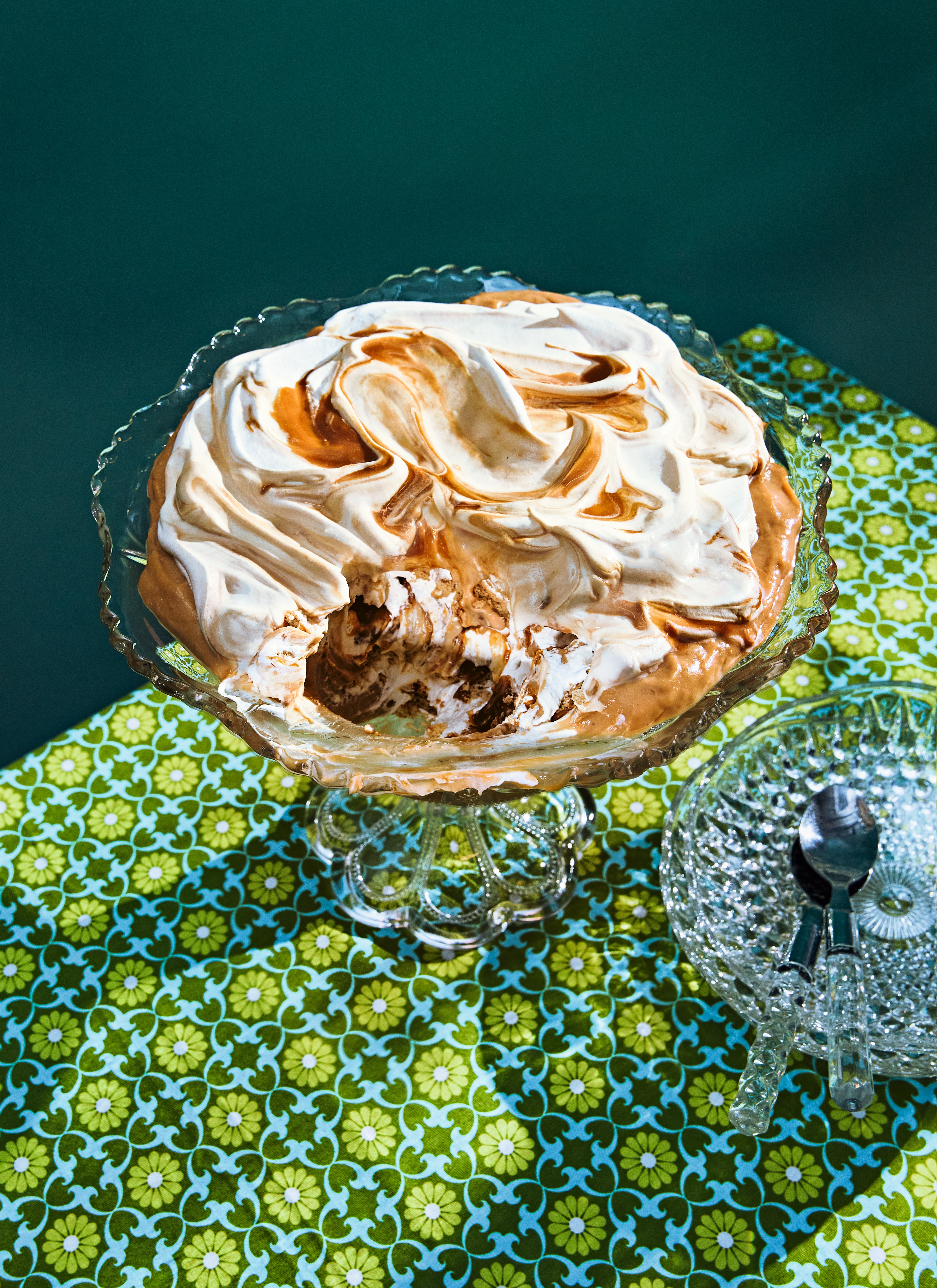 A banoffee pudding in a glass serving dish; some of the pie has been scooped out.