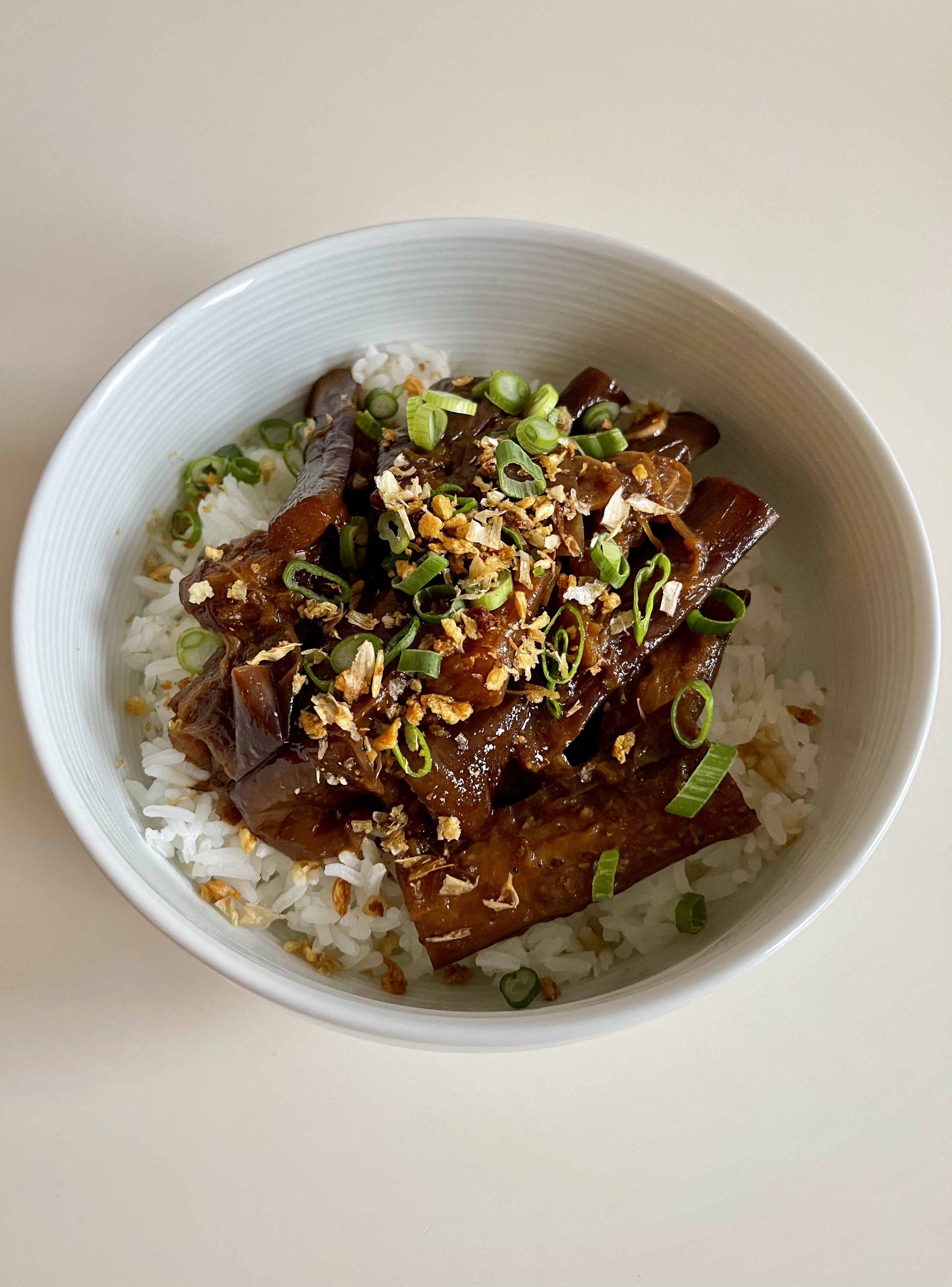 A bowl of eggplant adobo over white rice.