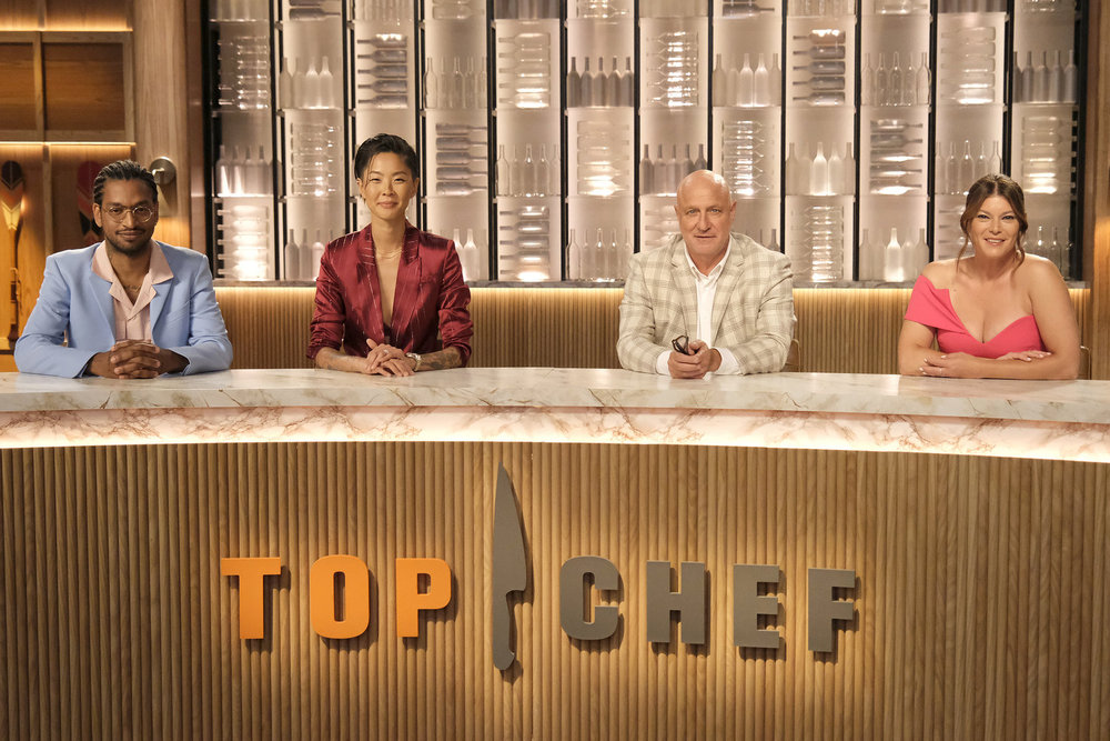 Four people sit behind a desk with the Top Chef logo.